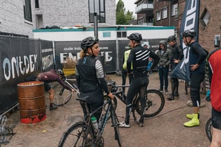 Riders gather around a bike-wash area with hoses and a rusty oil drum after the Backyard Breakaway.