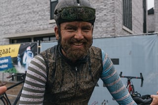 Smiling bearded rider covered in mud after the Scope Backyard Breakaway gravel ride in Eindhoven.