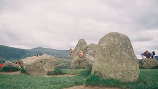 Riders peer out from behind standing stones at a stone circle near Keswick during the Low Key Lakes Weekender.