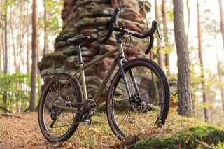 Tout Terrain Vasco steel gravel bike with drop bars and tan-wall tyres, seen from low down in front of a rock.