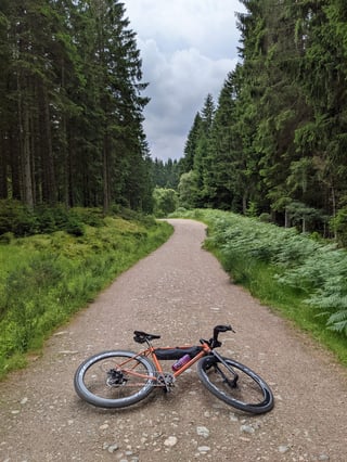 Orange Fairlight Secan with Scope R4A wheels lies on a gravel forest track on the Deeside Way.