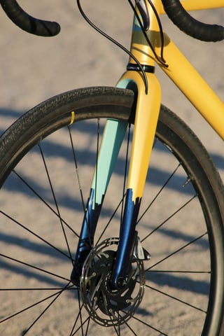 Wish One SUB fork painted yellow, turquoise and navy, with a disc rotor and Mavic front wheel.