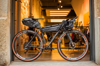 Belle Cycles A.T.E.R. side on in a shop doorway, with Cordel frame, bar and saddle bags and ENVE wheels.