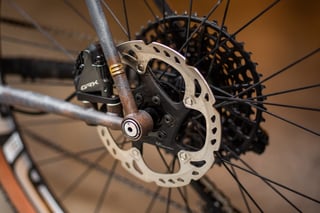 Rear disc rotor and Shimano GRX brake calliper on the A.T.E.R., with rusted dropout and wide-range cassette.