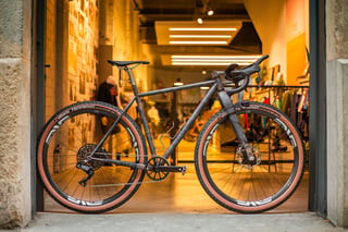 Belle Cycles A.T.E.R. built for the Atlas Mountain Race, a weathered steel gravel bike with ENVE wheels, in a shop doorway.