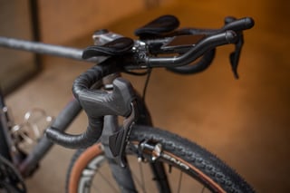 Shimano GRX Di2 shifter and brake lever on the A.T.E.R.'s bar tape, with aero bar extensions and a head unit behind.