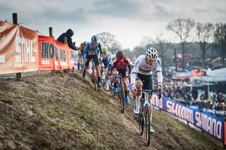 Mathieu van der Poel in the rainbow jersey leads a chasing group up a muddy climb at the Hoogerheide World Cup.