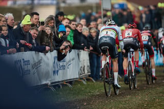 Mathieu van der Poel, number 1 on his back, chases two riders past fans leaning over the barriers at Hoogerheide.