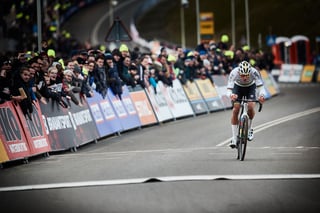 Mathieu van der Poel rides alone up the tarmac finishing straight at Hoogerheide, fans packed behind the barriers.