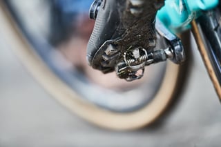 Close-up of a mud-caked shoe clipped into a Shimano SPD pedal on a turquoise-cranked cyclocross bike at Hoogerheide.