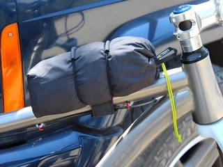 A Backcountry Research Super 8 strap holding a rolled-up Arc'teryx jacket to the top tube of a bike.