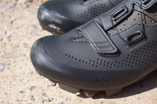 Toe of a black Fizik Terra X5 shoe with the perforated upper, reinforced toe cap and fizik logo.