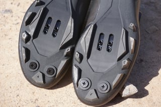 Forefoot of both Fizik Terra X5 soles showing the SPD cleat slots, stud threads and deep angular tread.