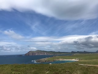 Grassy clifftop above a deep blue bay with a sandy cove and headlands, Dingle Peninsula, Kerry.