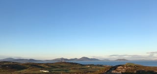 Evening light over hills and sea along the Wild Atlantic Way coastline in Donegal, a house in the foreground.