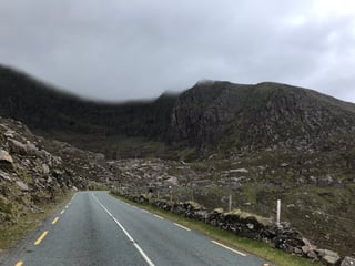 Empty road climbs beneath mist-covered crags in the Kerry mountains on day seven of the TransAtlantic Way.
