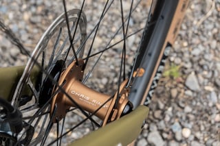 Chris King front hub in bourbon on a Sharp carbon wheel, with a disc rotor and olive Bombtrack Hook EXT fork.