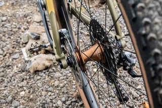 Chris King R45 rear hub in bourbon on the Bombtrack Hook EXT, with the SRAM cassette and a loose pedal on the gravel.