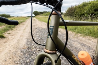 Handlebar tape, gear cables and bourbon Chris King headset on the Bombtrack Hook EXT, with a bottle in the cage.