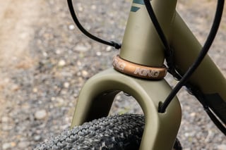Chris King headset in bourbon at the head tube of the Bombtrack Hook EXT, with gear cables and the fork crown.