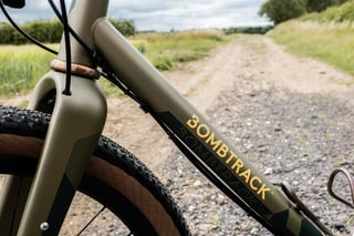 Bombtrack down tube logo and Chris King bourbon headset on the Hook EXT, with a Teravail tyre on a gravel track.