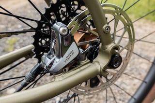SRAM Force flat-mount rear disc brake caliper on the Bombtrack Hook EXT's olive frame, with a 140mm rotor.