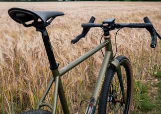 Low view over the Brooks saddle and Ritchey bars of the Bombtrack Hook EXT in a barley field.