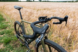 Bombtrack Hook EXT drop bars with SRAM Force lever and Wahoo computer, looking back along the bike in a cereal field.