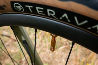 Peaty's x Chris King bourbon tubeless valve on the carbon rim beneath Teravail tyre lettering.