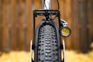 Front rack and Sinewave Cycles light on the Horse Cycles Monster Gravel, seen head-on above the knobbly front tyre.