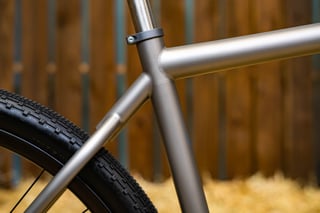 Titanium seat tube and top tube junction on the Moots Routt 45, with a seat clamp and the rear tyre alongside.