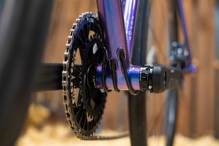 Purple-to-blue colour-shift paint on a bottom bracket shell with a Rotor chainring and internal cable ports.