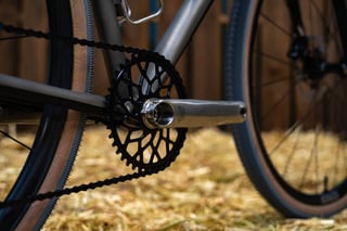 Black lattice chainring and polished crank arm on the Sklar All Road, with a tan-wall tyre behind.