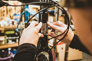 Hands fit the new Cotic head badge to the black head tube of the Escapade during the conversion.