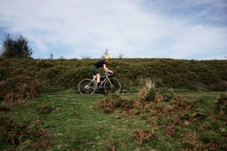 Side view of the Temple Adventure Disc 1 ridden along a grassy bank above heather in the Quantock Hills.