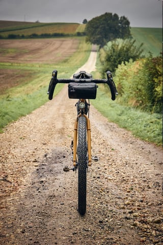 Front view of the Fairlight Faran 2 on a gravel track, with a Straight Cut Design handlebar bag and dynamo light.