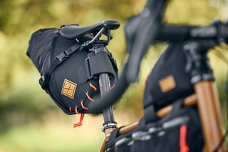 Restrap saddle pack with orange cords on the Winter Bracken Fairlight Faran 2, frame bag blurred behind.
