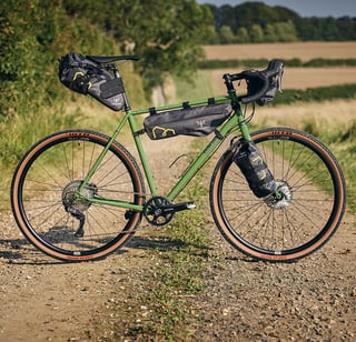 Woodland Green Fairlight Faran with a full Apidura bag set, GRX cranks and WTB Byway 44 tyres, on a gravel track.