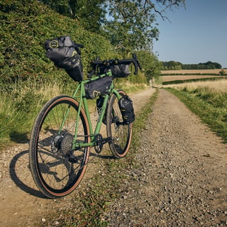 Fairlight Faran in Woodland Green with Apidura saddle pack, frame pack, handlebar pack and fork packs on gravel.