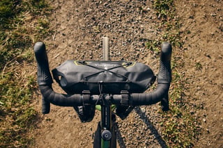 Apidura Expedition handlebar pack on the Woodland Green Fairlight Faran, seen from above on a dirt track.