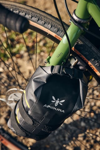 Close-up of an Apidura Expedition fork pack strapped to a King Cage mount on the Fairlight Faran fork.