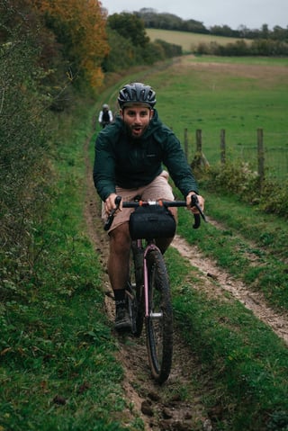 Rider on the pink Brother Cycles Kepler gapes at the camera while climbing a rutted grass bridleway on the Kent recce.