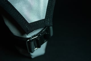 Close-up of the buckle and black webbing trim on a reflective grey Wiz Viz pouch from Wizard Works.