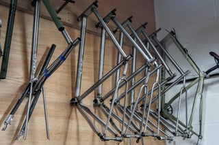 Rack of unpainted steel frames and forks hanging on the wall of the Stayer Cycles workshop.