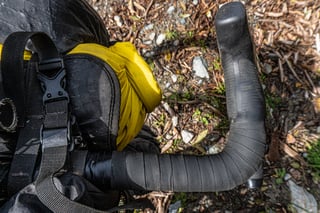 Top-down view of the Curve Walmer drop bar tape and a lever hood beside a yellow bag and bag strap.