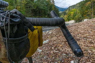 Curve Walmer 55cm bar end flaring outwards beside a yellow handlebar roll, with forested valley behind.