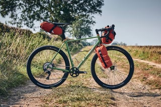 Woodland Green Fairlight Faran 2 with Road Runner saddle, handlebar and fork bags on a dry farm track.