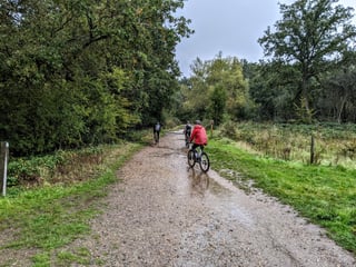 Three riders on a wet gravel track through Epping Forest, one in a red jacket, on the Stayer Groadinger UG test ride.