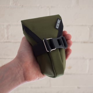 Small Teeny Houdini in olive green, held in a hand to show its size.