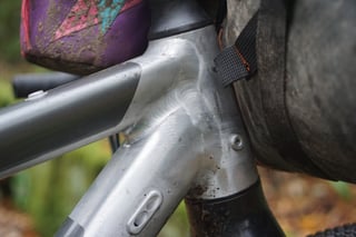Welded head tube junction on the raw alloy Riverside 920 prototype frame, with muddy bags strapped behind it.